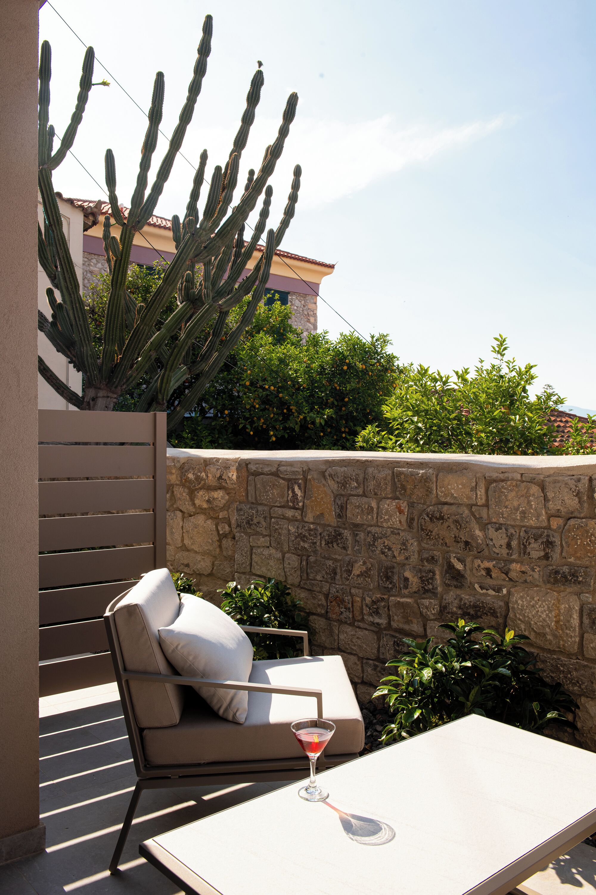 Une terrasse avec un fauteuil confortable, une table et un verre à martini.