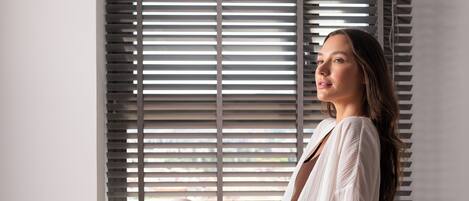 A person sitting on a bed with a window in the background.