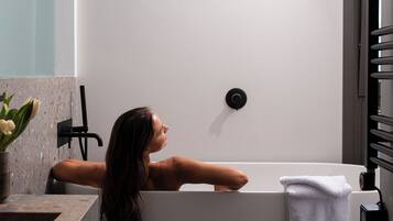 A modern bathroom with a freestanding bathtub, a towel rack, and a showerhead.