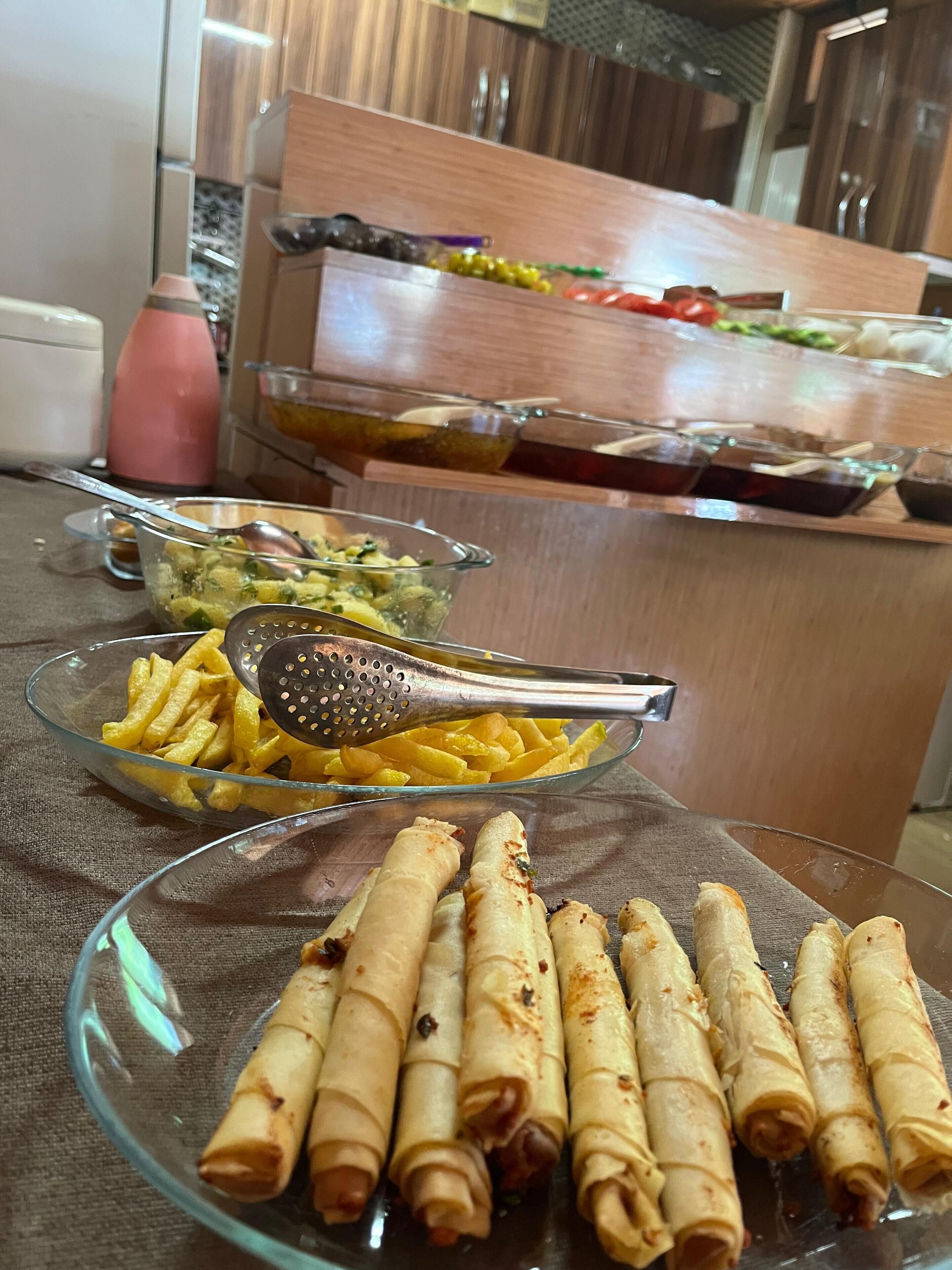 A buffet table with various dishes including fried items, a salad, and a beverage dispenser.