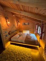 Un dormitorio de cabaña de madera con una cama, un tapete mullido, una pared de madera con un letrero que dice 'Paradise' y una decoración rústica que incluye un cráneo y un farol.