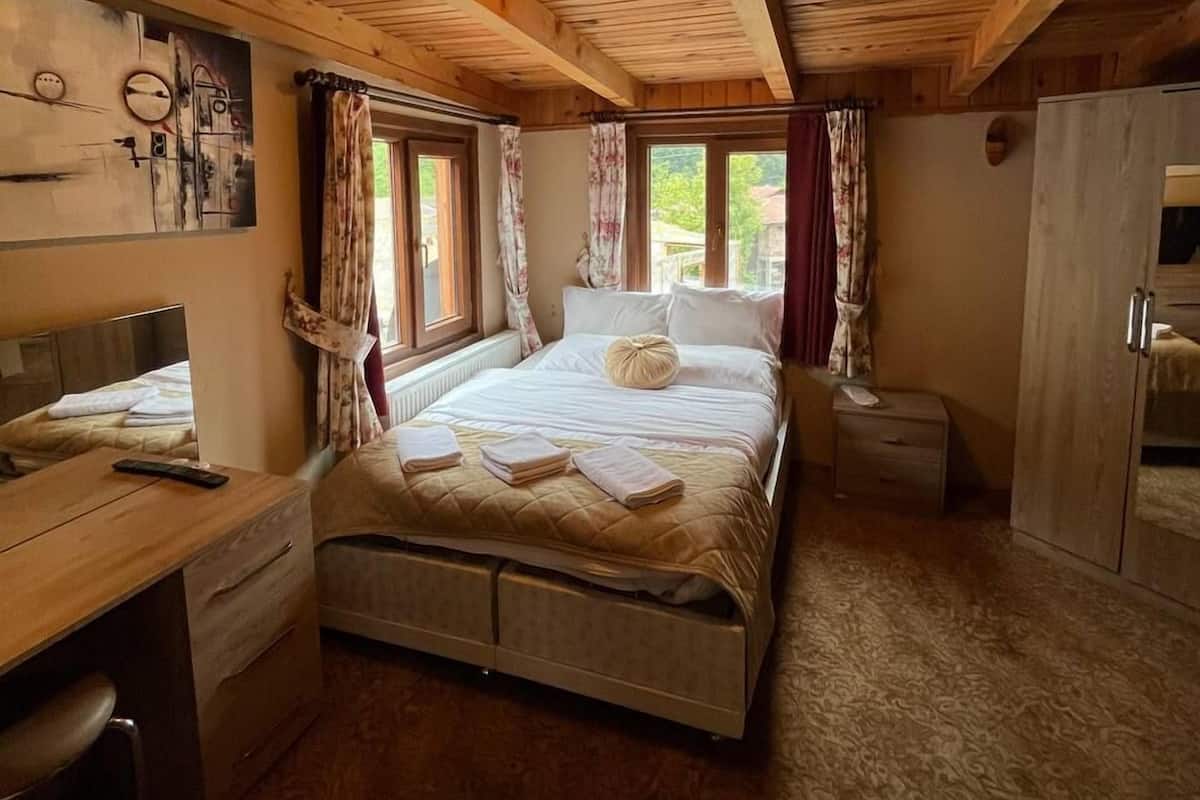 A wooden cabin-style bedroom with a bed, bedside table, and a wardrobe.
