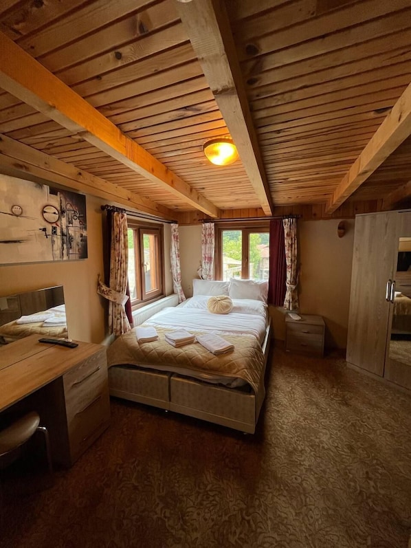 A bedroom with a wooden ceiling, a bed, a desk, and a wardrobe. - Ayder Paradise Otel (Camlihemsin)