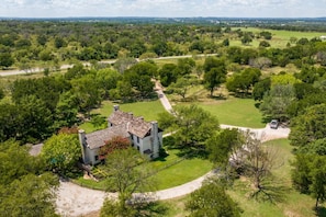 Une vue aérienne d’un vaste domaine, avec un bâtiment central entouré d’une végétation luxuriante et de vastes champs.
