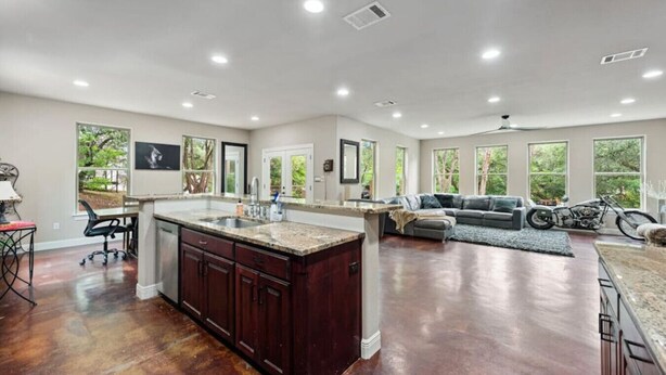 A spacious kitchen with a large island, a dining area with a sofa, and a motorcycle in the background. - Hill Country Hideaway (Austin)