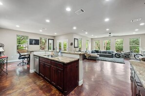 A spacious kitchen with a large island, a dining area with a sofa, and a motorcycle in the background.