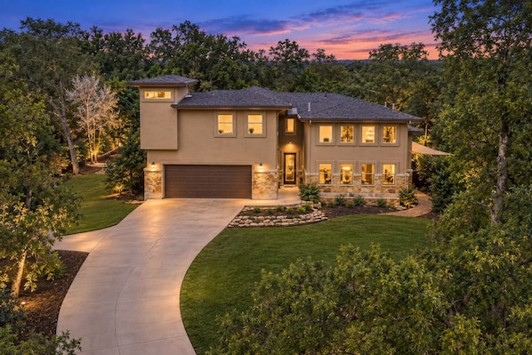 A two-story house with a garage, a driveway, and a well-maintained lawn.