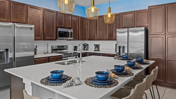 A modern kitchen with dark wooden cabinets, stainless steel appliances, and a central island with blue bowls.
