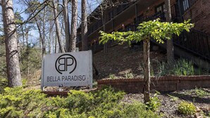 A sign for Bella Paradiso with a view of a building and trees.