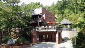 A rustic building with a balcony and a gazebo, surrounded by trees.