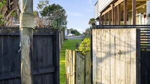 A wooden gate leading to a property with a visible house and a grassy yard. - Sandy Feet Retreat - Papamoa (Papamoa)