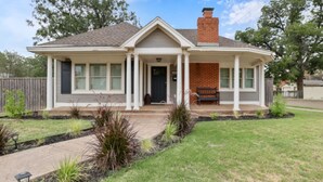 A single-story house with a front porch, a chimney, and a well-maintained lawn.