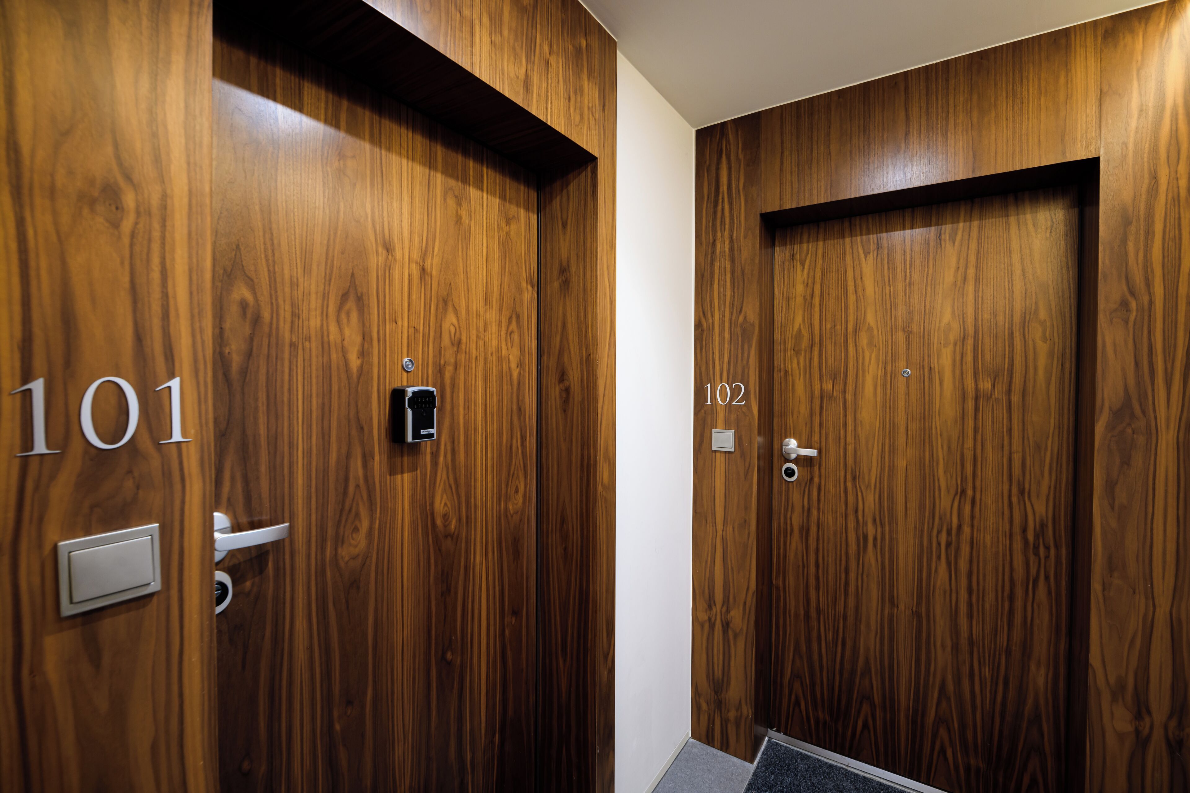 Two wooden doors with numbers 101 and 102, each with a doorbell and a door handle.