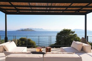 Un espacio de estar al aire libre cubierto, con vistas al mar y a las montañas.