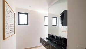 Casa de banho moderna com bancada de mármore, um espelho grande e uma moldura com imagem na parede.