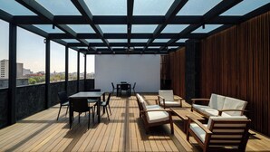 Terraço no telhado com deck de madeira, mobiliário de exterior e vista da cidade.