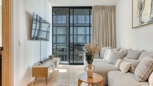 Uma sala de estar moderna com um sofá, uma mesa de centro e uma TV na parede.