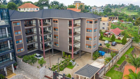 A multi-story hotel with balconies, a courtyard, and surrounding greenery.