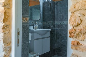 A bathroom with a sink, mirror, and shower.