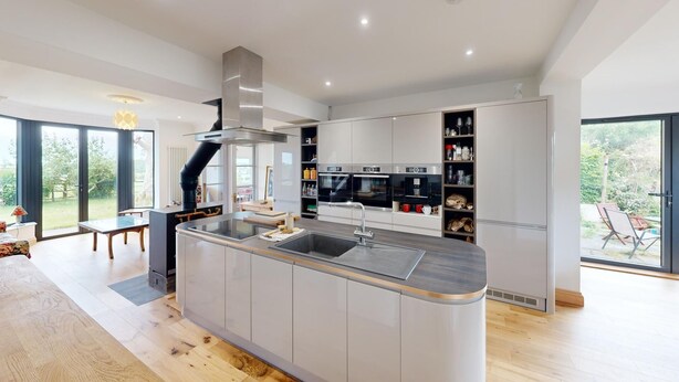 Una cocina moderna con una isla central, electrodomésticos integrados y vistas al exterior.