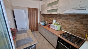 Cocina compacta con refrigerador, microondas, estufa y armarios de madera.
