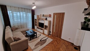 Una sala de estar con sofá, mesa de centro, mueble para televisión y una puerta de madera.