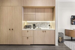 Een moderne keuken met houten kasten, een marmeren aanrecht en een koffiezetapparaat.