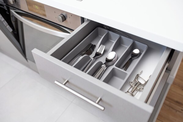 A kitchen drawer with utensils and a stove in the background. - Native Apartments Blich 7 (Kraków)