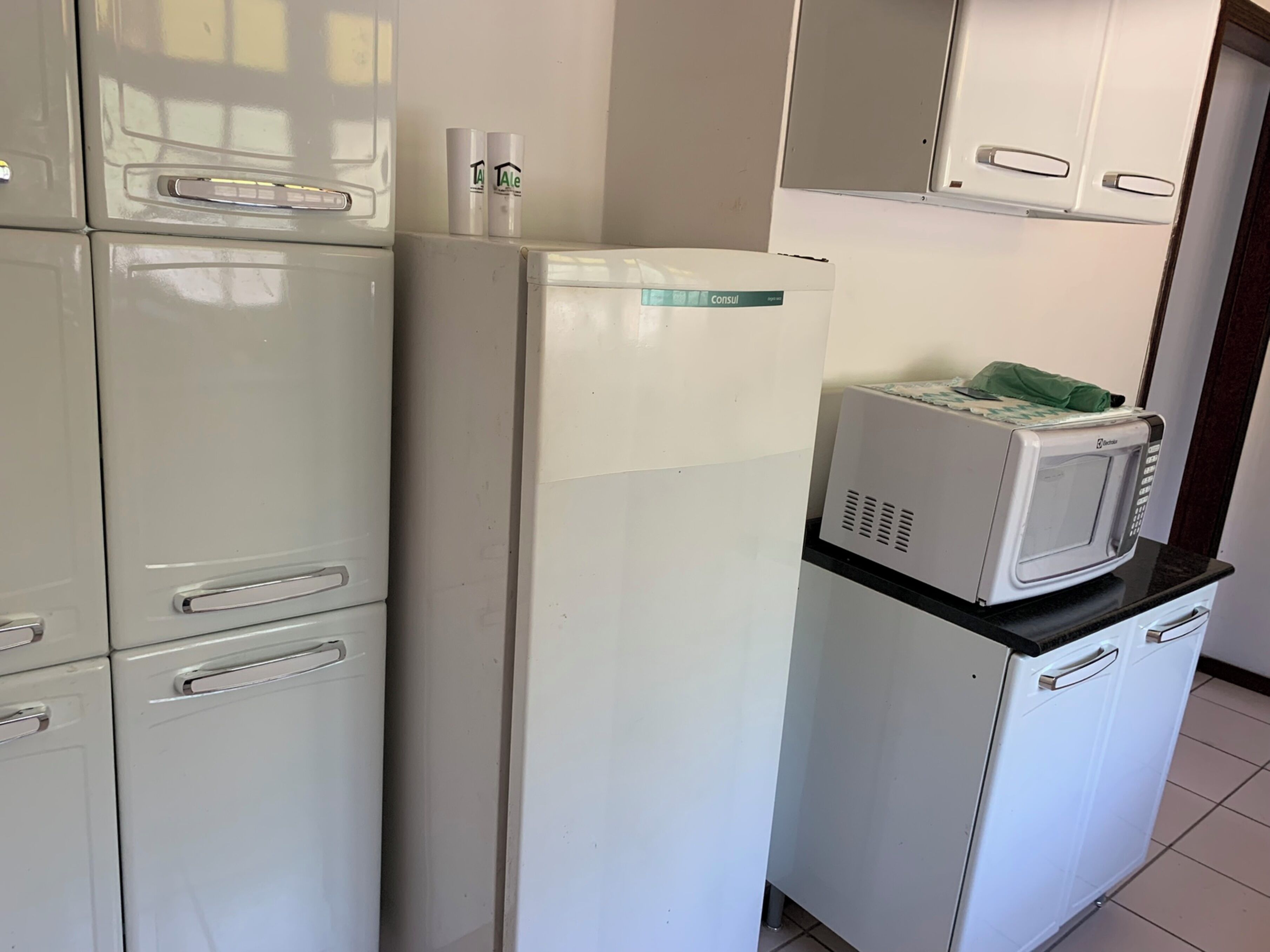 A compact kitchen with white appliances, including a refrigerator, a microwave, and a small oven.