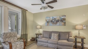 A living room with a grey sofa, patterned armchair, and two side tables with lamps. - Grand Comfort: 2 BR w/ Golf Cart & Bay Views at Sandestin Golf and Beach Resort! (Miramar Beach)
