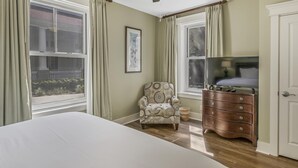 A bedroom with a bed, a chair, a dresser, and a television. - Grand Comfort: 2 BR w/ Golf Cart & Bay Views at Sandestin Golf and Beach Resort! (Miramar Beach)