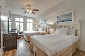A bedroom with two beds, a ceiling fan, and large windows.