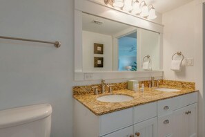 A bathroom with two sinks, a large mirror, and a towel rack.