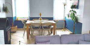 Un coin repas avec une table et des chaises, un canapé, une lampe sur pied et une plante en pot.