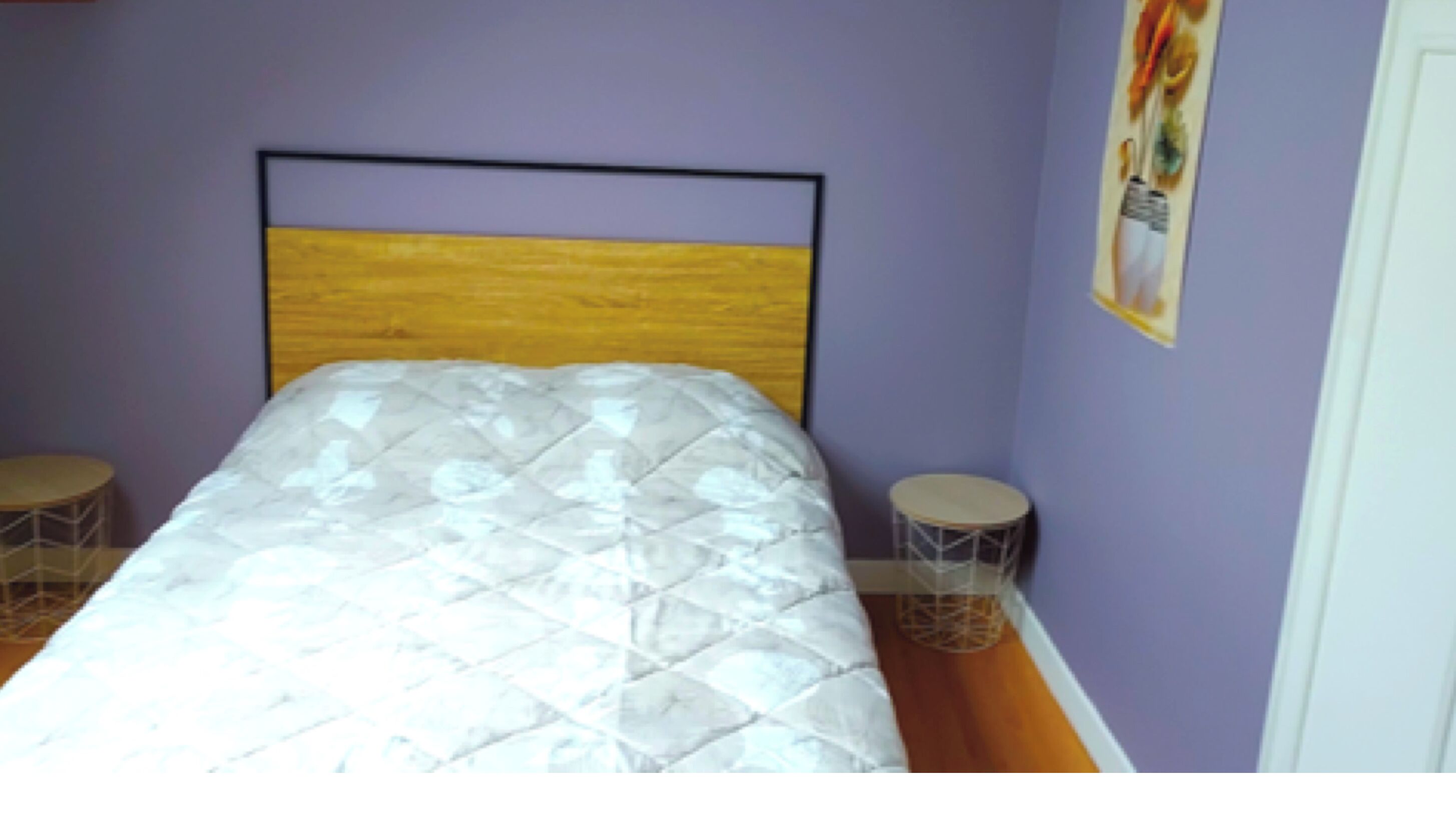 A bedroom with a bed, two side tables, and a wall with a poster.