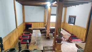 Una stanza tradizionale in legno con tatami, un tavolo lungo e diversi oggetti in ceramica.