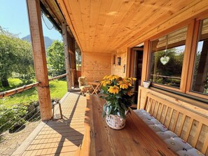 A wooden cabin with a porch, a table with chairs, and a basket of flowers.