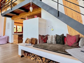 A modern living room with a wooden staircase, a sofa with various cushions, and a fireplace. - Kitzcharme Penthouse Ski & Golf by Belle-stay (Kitzbühel)