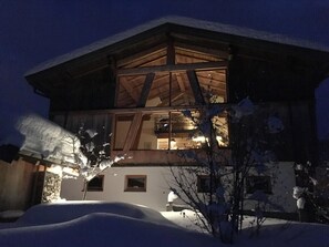 Ein schneebedecktes Gebäude mit einer Holzfassade und großen Fenstern.