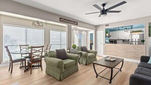 A spacious living room with a dining area, a kitchen in the background, and a ceiling fan. - Catching Rays-Heated Pool-Family and Pet Friendly (Destin)