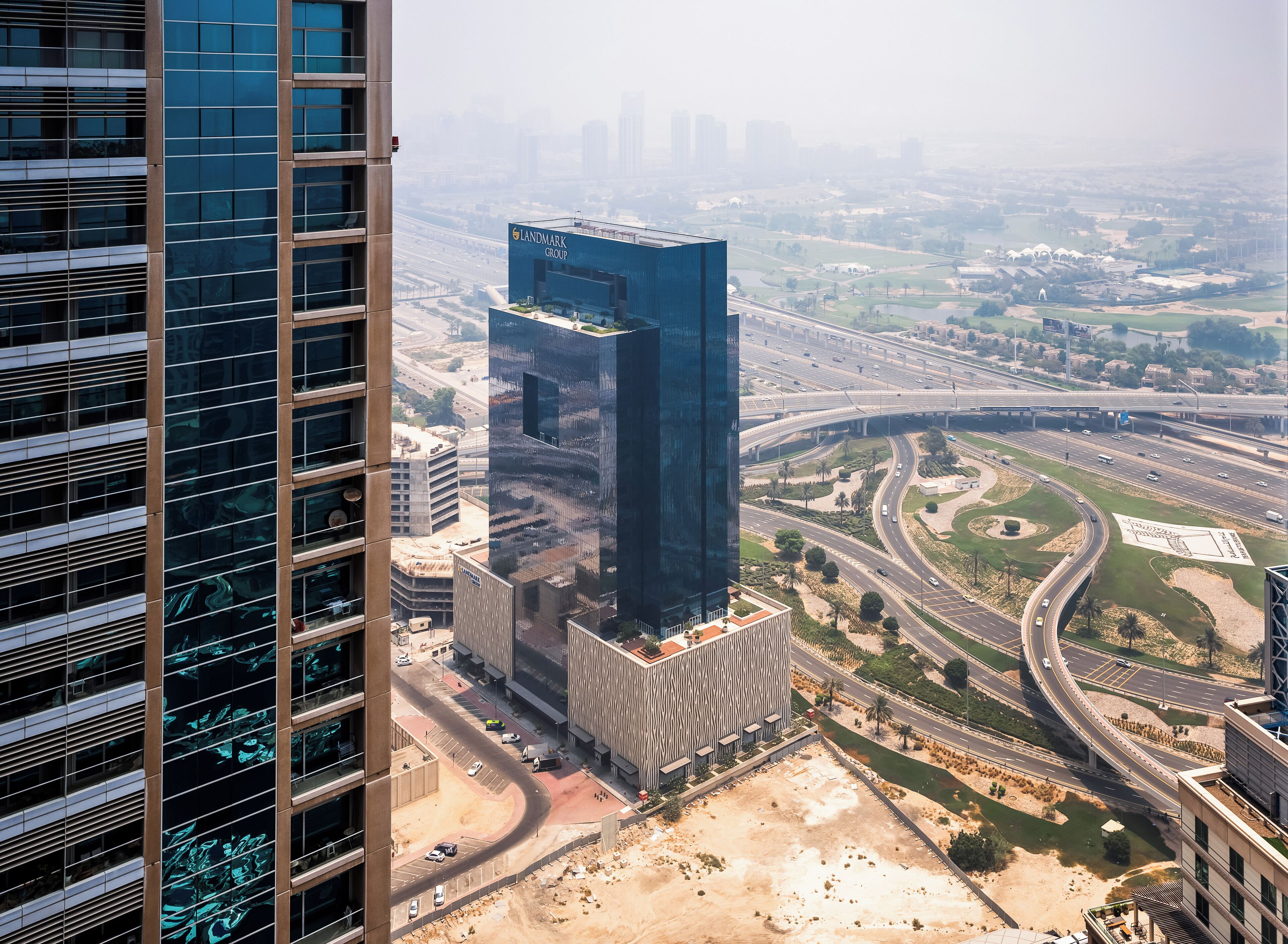 Un moderno grattacielo con facciata in vetro e un cartello ben visibile con la scritta 'Landmark Group'.