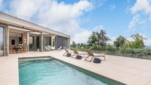 A modern house with a swimming pool, outdoor seating, and a view of the surrounding landscape. - Futuriste - Exceptional residence with panoramic view (Saint-Didier-au-Mont-d'Or)