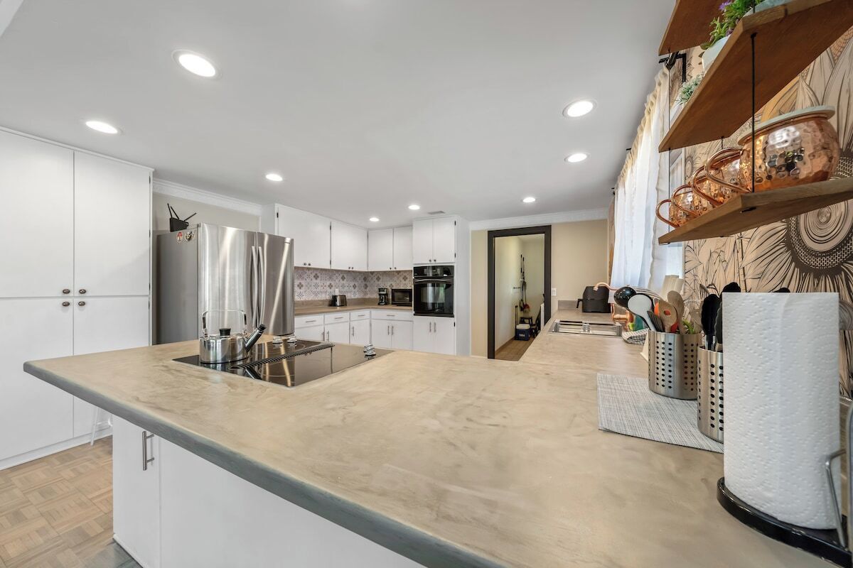 A modern kitchen with white cabinets, stainless steel appliances, and a marble countertop.