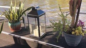 A table with a potted plant, a lantern, and a small tree. - Pura Vida- Floating Home (Merritt Island)