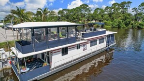 A houseboat with a covered deck, a kitchen area, and a bathroom. - Pura Vida- Floating Home (Merritt Island)