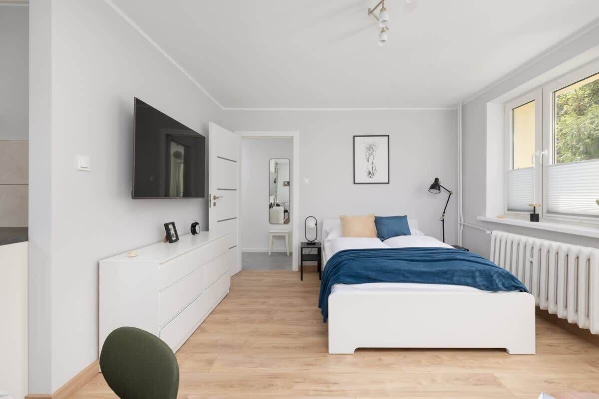 A modern bedroom with a bed, bedside table, and a TV mounted on the wall.