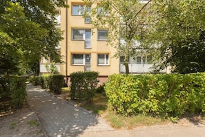 A multi-story residential building with a paved pathway leading to the entrance.
