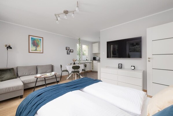 A modern bedroom with a bed, a sofa, a desk, and a TV.