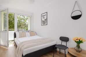 Ein modernes Schlafzimmer mit einem Bett, einem Sessel, einem kleinen Tisch mit Blumen und einer Pendelleuchte.