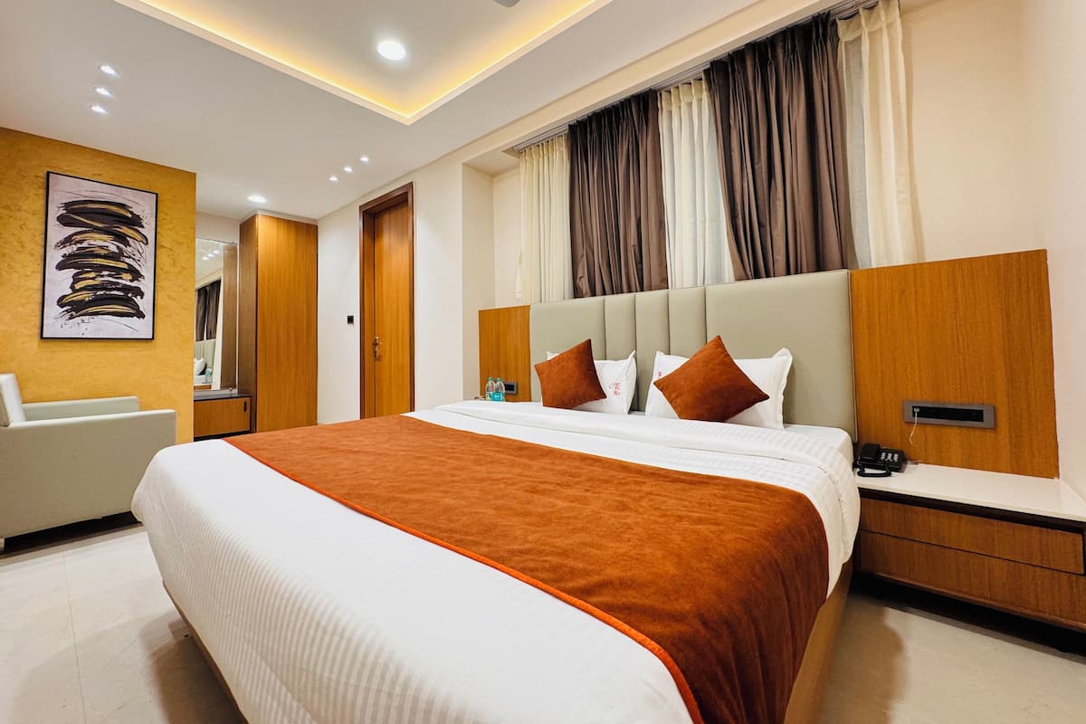 A modern hotel room with a large bed, a bedside table, a mirror, and a ceiling fan.